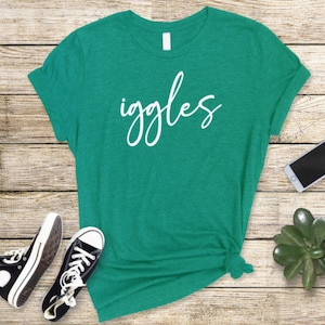K&ouml;nnte beinhalten: Ein t&uuml;rkisfarbenes T-Shirt mit dem Wort "giggles" in wei&szlig;er Kursivschrift.