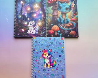 May include: Three spiral-bound notebooks with fantasy-themed covers. One features a white dragon in a forest with glowing butterflies. Another shows a blue dragon on a mushroom. The third has a colorful wolf on a blue background.