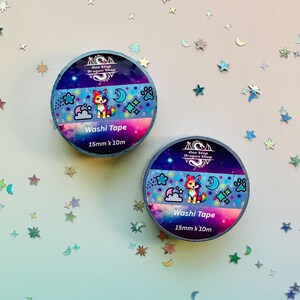 May include: Two rolls of washi tape with a colorful cat design. The tape features a cat, stars, clouds, and paw prints on a blue and pink background. Each roll is 15mm x 10m.