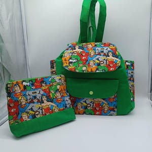 May include: Green backpack and matching pouch set. The backpack features a green flap, pocket, and straps, with a colorful comic book character print on the front. The pouch has a zipper closure and the same comic book character print.