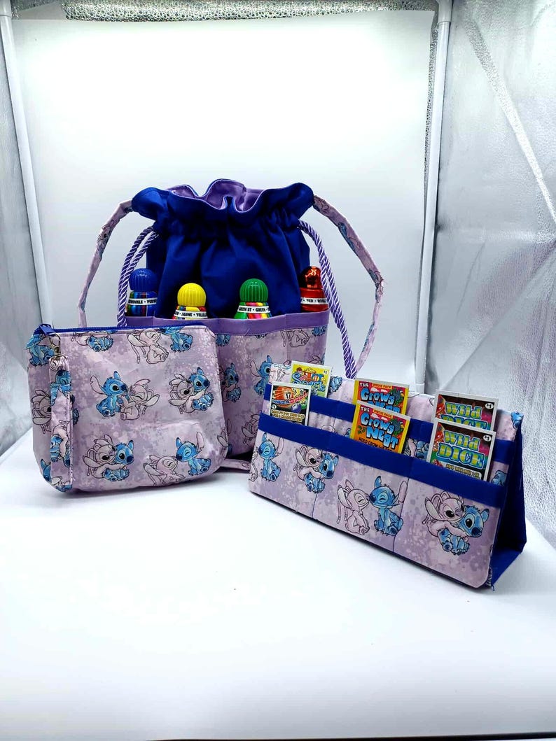 May include: A set of three fabric organizers featuring a Stitch character print. Includes a drawstring bag with bottles, a zippered pouch, and a card holder. The drawstring bag is blue with a purple lining.