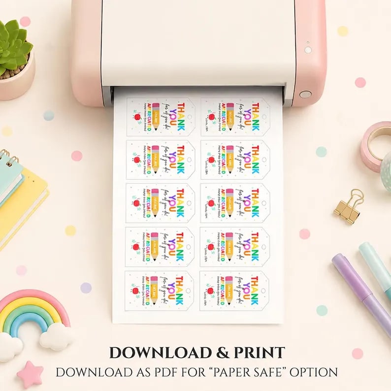 May include: A pink printer is printing a sheet of white gift tags. Each tag has a yellow pencil, a red apple, and the words "THANK YOU" printed on it. The tags are for teachers. The bottom of the image says "DOWNLOAD & PRINT".