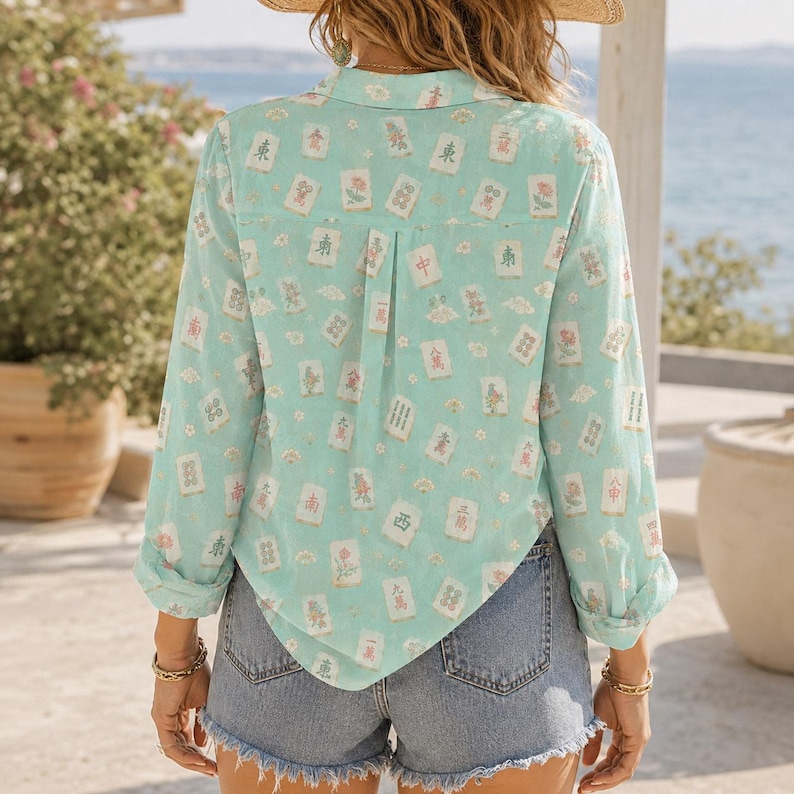 May include: A light turquoise long-sleeve button-down shirt featuring an all-over print of various mahjong tiles, paired with blue denim shorts that have a frayed hem. The shirt has a collar, a back yoke, and a center back pleat detail.