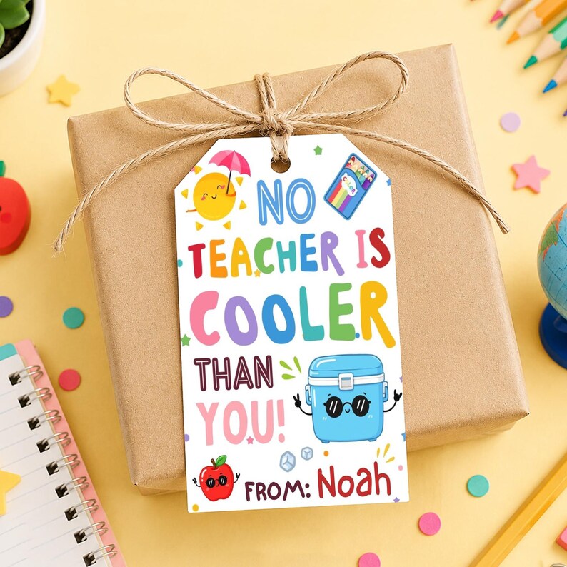 May include: A gift box wrapped in brown paper with a twine bow. A white tag reads "NO TEACHER IS COOLER THAN YOU!" with colorful illustrations of a sun, lunchbox, and apple. The tag says "FROM: Noah".
