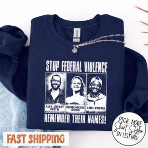 May include: Navy blue sweatshirt with the text "STOP FEDERAL VIOLENCE" and the names Alex Jeffrey Pretti, Renee Nicole Good, and Keith Porter. The phrase "REMEMBER THEIR NAMES!" is below the names. A silver necklace is draped across the top.