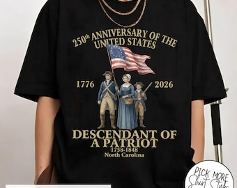 May include: Black t-shirt featuring a graphic commemorating the 250th anniversary of the United States. The design includes an American flag, the years 1776 and 2026, and the text "Descendant of a Patriot."