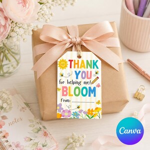 Può includere: Un regalo confezionato con un fiocco color pesca e un'etichetta regalo con la scritta "Thank You for helping me! Bloom". L'etichetta presenta un girasole, api, una matita e fiori. Il regalo è su una superficie bianca con fiori e un taccuino.