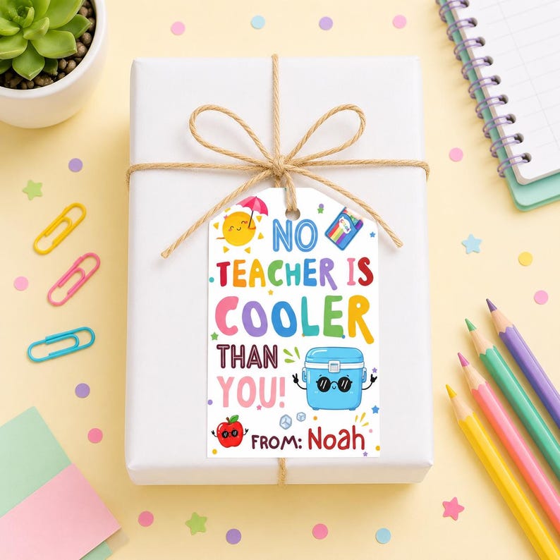 May include: A white gift box tied with twine, featuring a colorful tag that reads "No Teacher Is Cooler Than You!" with illustrations of a sun, cooler, and apple. The tag also includes the text "From: Noah."