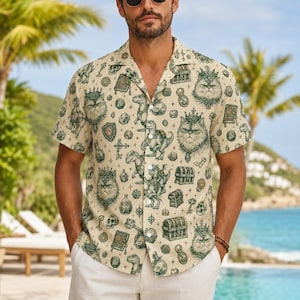 May include: A short-sleeved button-down shirt in a light beige color featuring an all-over dark green print. The pattern includes illustrations of cats wearing crowns, dinosaurs, treasure chests, skulls, books, keys, and various geometric dice.