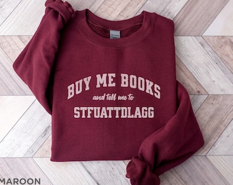 Puede incluir: Sudadera color granate con el texto "BUY ME BOOKS and tell me to STFUATTDLAGG" impreso en la parte delantera.