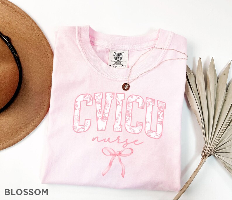 May include: Pink t-shirt with a floral design that says "CVICU nurse" with a pink bow.