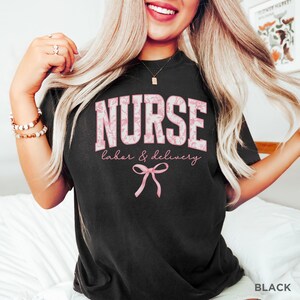 May include: Black t-shirt with a pink floral design that says "NURSE labor & delivery" with a pink bow underneath.
