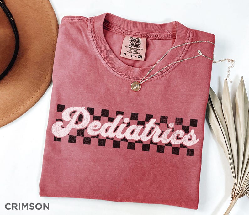 May include: A crimson red t-shirt with a white checkered design and the text "Pediatrics" in a retro font.