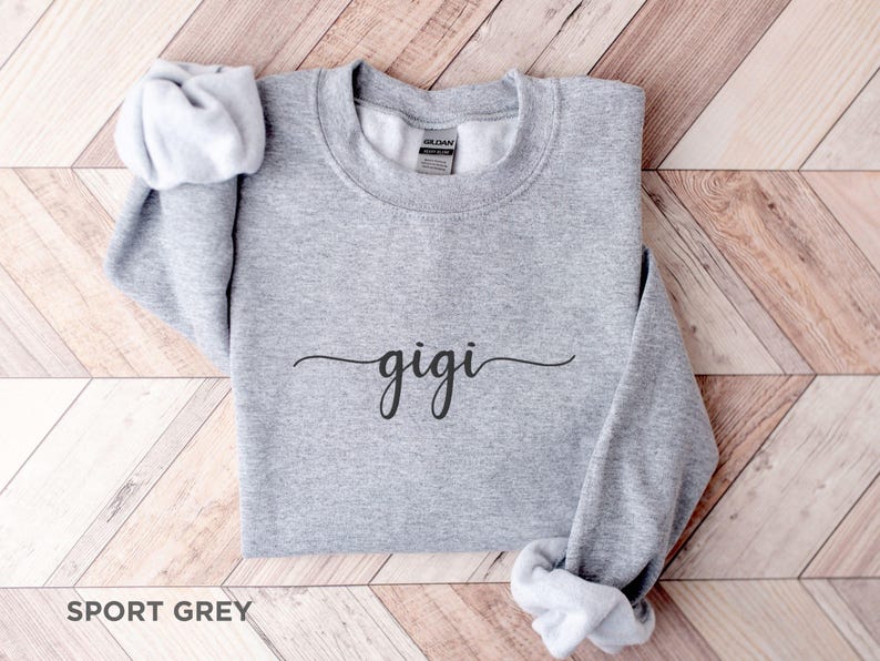 May include: A gray sweatshirt with the word "gigi" written in cursive on the front. The sweatshirt is made of a soft, comfortable material and is perfect for everyday wear.