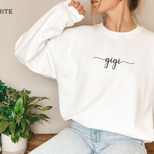 May include: White sweatshirt with the word "gigi" written in cursive on the front.