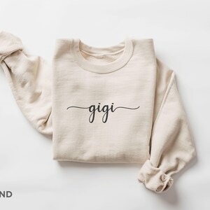 May include: A sand-colored sweatshirt with the word "gigi" written in cursive on the front.