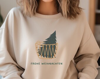 May include: A beige sweatshirt with a graphic of a Christmas tree in a basket. The text "Frohe Weihnachten" is printed below the graphic.