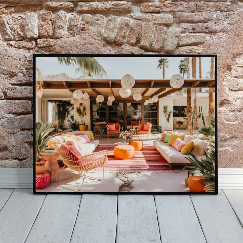 Op de afbeelding: Een modern terras in mid-century stijl met witte rieten meubels, roze en oranje kussens en een gestreept tapijt. Witte papieren lampionnen hangen aan het plafond en cre&euml;ren een feestelijke sfeer.
