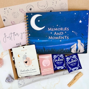 May include: A gift box with a journal featuring a moon and stars design, a pink card with "Just for you" text, a face mask, affirmation cards, and two "night time" tea sachets. A piece of Palo Santo is also included.