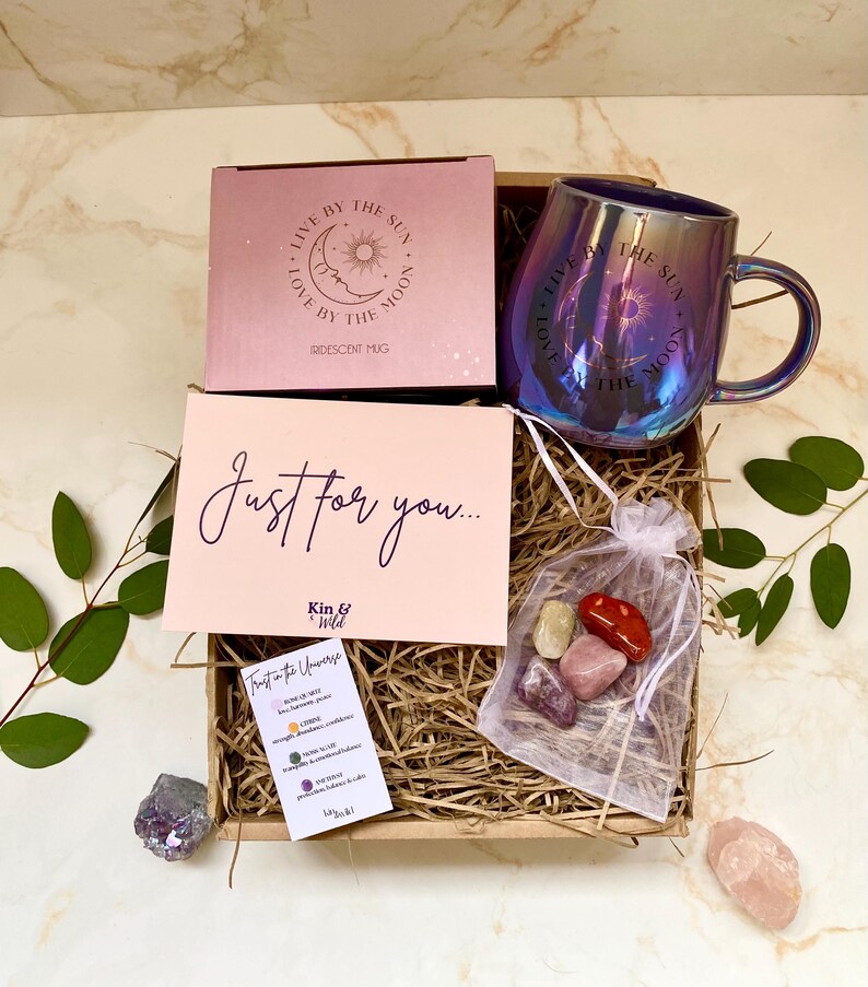 May include: A gift box with a pink iridescent mug, a pink box, a card with the text "Just for you...", a small bag of stones, and greenery. The mug has the text "Love by the moon" and "Live by the sun".