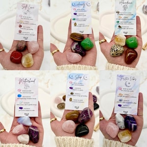 May include: Six sets of polished tumbled gemstones, each accompanied by a descriptive card labeled with themes like Self Love, Anxiety, Abundance, Motherhood, Sleep, and Positive Vibes, detailing specific stone names and their properties.