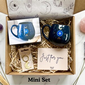 Op de afbeelding: Cadeaudoos met een donkerblauwe mok met een boze oog-ontwerp, een halve maan sleutelhanger en een kaart met de tekst "Just for you...". De doos bevat ook een rozenkwartskristal en amethiststenen. De tekst "Mini Set" staat onderaan.