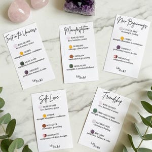 May include: A collection of crystals and affirmation cards. The crystals include rose quartz, amethyst, and other stones. The cards feature phrases like "Trust in the Universe" and "Self-Love", with details about each crystal's properties.