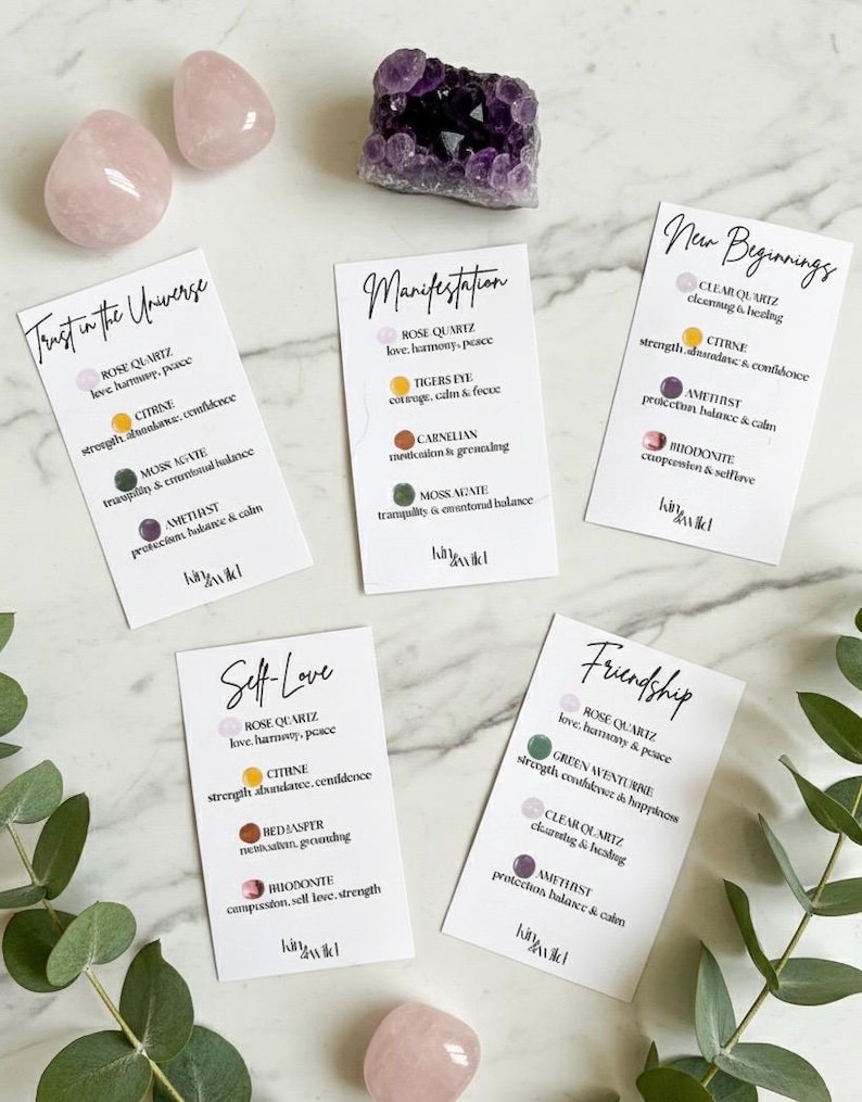 May include: A collection of crystals and affirmation cards. The crystals include rose quartz, amethyst, and other stones. The cards feature phrases like "Trust in the Universe" and "Self-Love", with details about each crystal's properties.