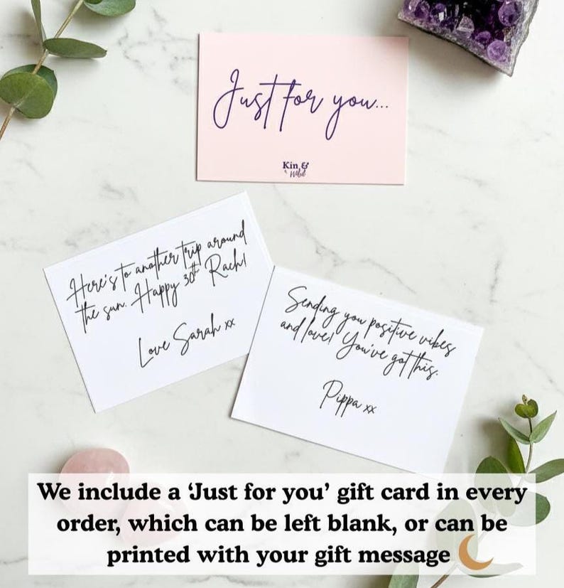 May include: Three gift cards on a marble surface. One pink card reads "Just for you..." in cursive. Two white cards have handwritten messages. Greenery and a crystal are in the background. The cards are for gifts.