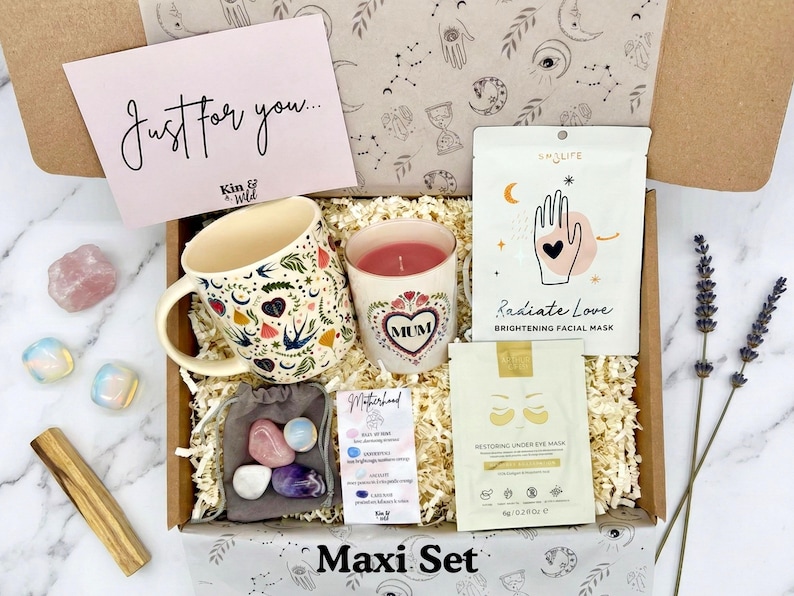 May include: A gift box with a mug, candle, facial mask, eye mask, crystals, and a card that says "Just for you." The mug and candle have floral and heart designs. The box is labeled "Maxi Set."
