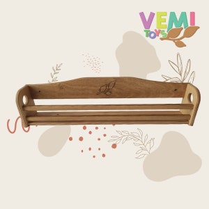 May include: A wooden shelf with two shelves and a leaf design on the front. The shelf is made of natural wood and has a rustic look. VEMI TOYS is printed on the top right corner of the image.