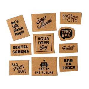 Könnte beinhalten: Zehn braune Papieretiketten mit schwarzem Text. Die Etiketten zeigen verschiedene Slogans rund um Taschen, darunter "Bags Appeal", "#QUARTER Bag", "Feed Bag", "Bag Street Boys" und "Bag On Track".