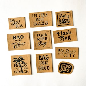 Könnte beinhalten: Eine Sammlung brauner rechteckiger Etiketten mit schwarzem Text. Die Etiketten zeigen Sätze wie "Bag Street Boys", "Let's Talk About Bags" und "Bag to Basic". Weitere Etiketten sind "Flash Bag" und "Bags and the City".