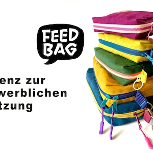 Könnte beinhalten: Ein Stapel aus fünf bunten Reißverschlusstaschen mit den Worten "Feed Bag" in einer Sprechblase. Die Taschen sind in den Farben Lila, Gelb, Grün und Blau. Der Text "Lizenz zur gewerblichen Nutzung" ist unterhalb der Sprechblase sichtbar.