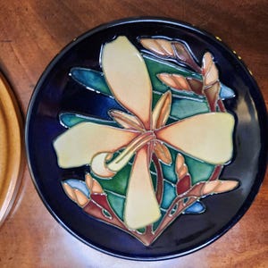 May include: A white ceramic mug with a black handle and the text "But First, Coffee" in a bold, black font. The mug is set against a blurred background, highlighting its simple design.