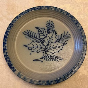 May include: A white ceramic mug with a black handle and the text "But First, Coffee" in a black, bold font. The mug is on a white surface.