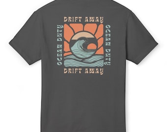 May include: A dark grey t-shirt with a graphic print of a wave and a sunset. The text "Drift Away" and "Ocean Duty" is printed on the shirt.