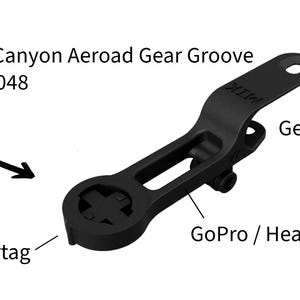 May include: Black plastic bike mount with a gear groove for attaching to a Canyon Aeroad bike. It has a slot for a GoPro or headlight and a mount for a Wahoo or AirTag.
