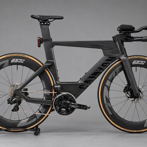 May include: A matte black Canyon Speedmax triathlon bicycle featuring deep-section Zipp carbon wheels with tan sidewall Continental tires, a streamlined aerodynamic frame, integrated aero handlebars, and a black saddle with a rear light.