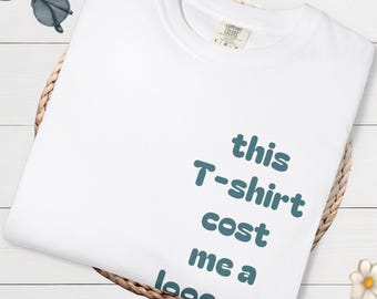 The Comfort Colors® T-shirt features the phrase "This T-shirt cost me a lot of money" and has a logo inspired by modern streetwear