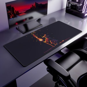 May include: A black rectangular gaming mouse pad featuring a pixelated illustration of a character wielding a flaming sword. The artwork uses shades of orange, red, and yellow against a dark background. The pad is designed for extended use.