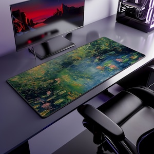 Puede incluir: Alfombrilla de escritorio rectangular con una pintura impresionista de un estanque de nenúfares. El diseño presenta tonos verdes, azules y naranjas, con un borde negro. La alfombrilla está sobre un escritorio con un monitor de ordenador y otros accesorios. Mide unos 80 cm de largo.
