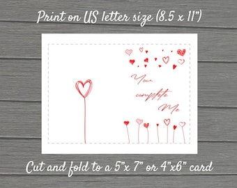 Può includere: Modello di carta stampabile con il testo "You complete me" e un design a forma di cuore rosso. La carta è progettata per essere tagliata e piegata in una carta di 5x7 pollici o 4x6 pollici.