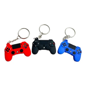 May include: Three different colored Playstation controller keychains. The keychains are red, black, and blue. Each keychain has a silver key ring.