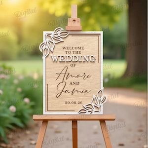 May include: A wooden wedding sign on an easel, featuring the names "Amari and Jamie" and the date "20.08.26". The sign has decorative leaf accents and the words "Welcome to the Wedding".
