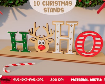 May include: A wooden Christmas sign with the word "HO HO" in red, green, and white letters. A reindeer head is between the first two letters. The sign is on a wooden base. The text "10 CHRISTMAS STANDS" is above the sign. The text "SVG-DXF-PNG-JPG 300 DPI MATERIAL WIDTH: 3MM" is below the sign.