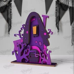 May include: A purple and pink Halloween-themed wooden house decoration. The house features a chimney, a door, and decorative trees. The window is orange. The material width is 3 mm. The house is on a wooden base.