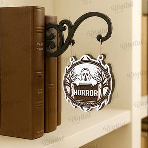 Peut inclure: Panneau d&eacute;coratif d'Halloween noir et blanc avec le mot "HORROR" et un dessin de fant&ocirc;me. Le panneau est suspendu &agrave; un crochet noir d&eacute;coratif, &agrave; c&ocirc;t&eacute; de livres bruns.