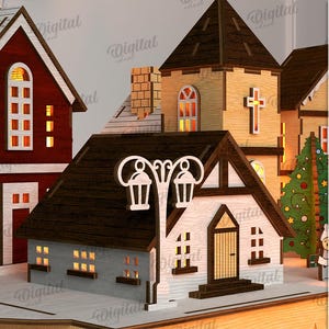 May include: A laser-cut wooden Christmas village scene with several buildings, including a church with a cross and a house with a street lamp. The buildings have illuminated windows. The material width is 3 mm.