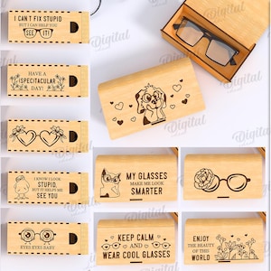 Op de afbeelding: Tien houten brillenkokers met gegraveerde ontwerpen en tekst, zoals "I Can't Fix Stupid" en "Enjoy the Beauty of This World". De kokers zijn gemaakt van licht hout en zijn 3 mm breed. Een bril ligt in een open koker.